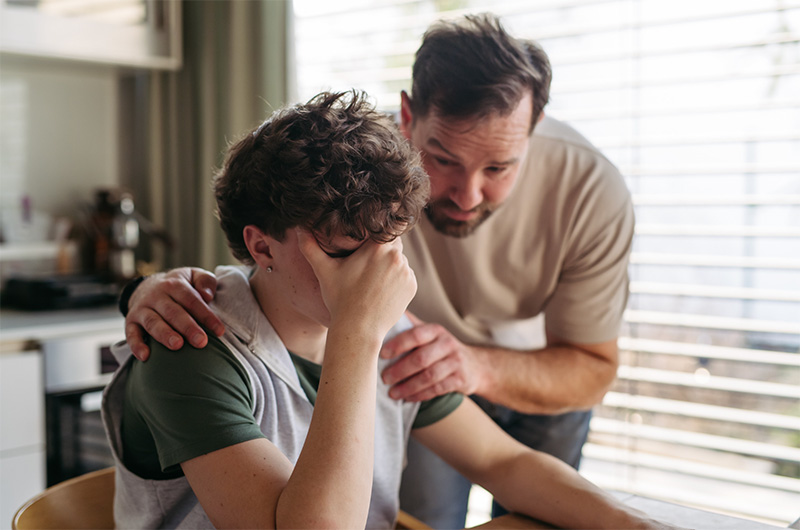 image of father comforting teenage son